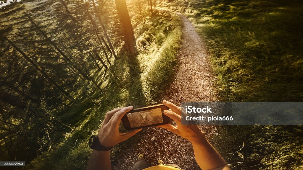 POV Trail running in the forest: checking map on mobile Personal Perspective Stock Photo