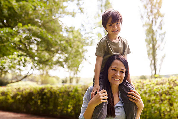 istock Mother Giving Son Ride On Shoulders During Walk 588394692