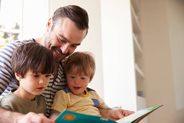 primer plano del padre y los hijos leyendo la historia en casa - familia con dos hijos fotografías e imágenes de stock