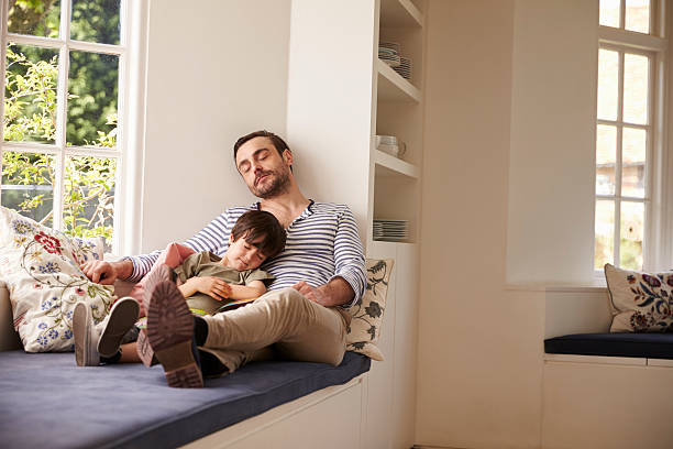istock Father And Son Sleeping On Window Seat At Home Together 588394764