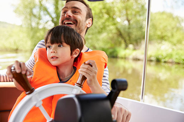 father and son enjoying day out in boat on river together - nautical vessel motorboating motorboat fun imagens e fotografias de stock