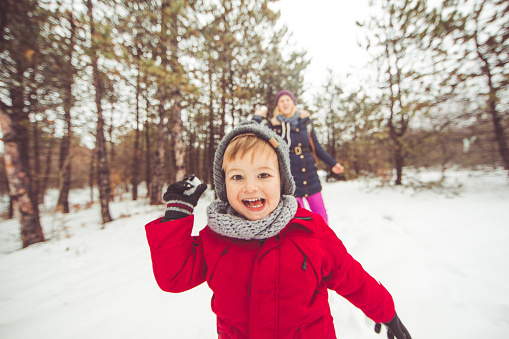 Smiling little boy and his mother having a great winter day outdoors playing in the snow