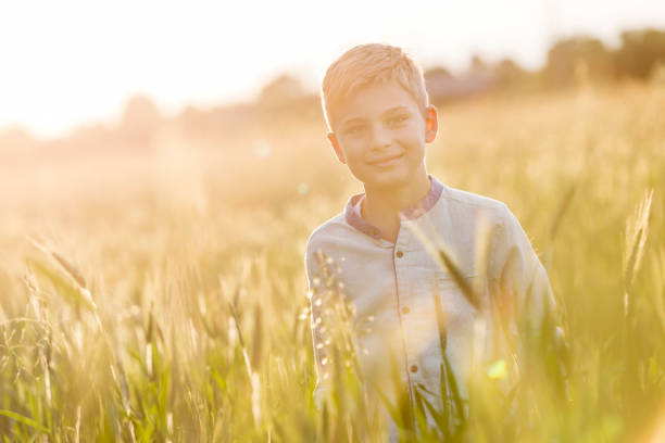 istock Portrait smiling boy in sunny rural wheat field 588482557