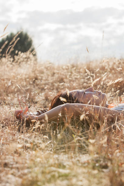 Sporty woman is doing relaxation exercise on grass.