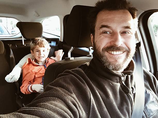 Smiling Father In Car With Son Sitting At Back Seat stock photo
