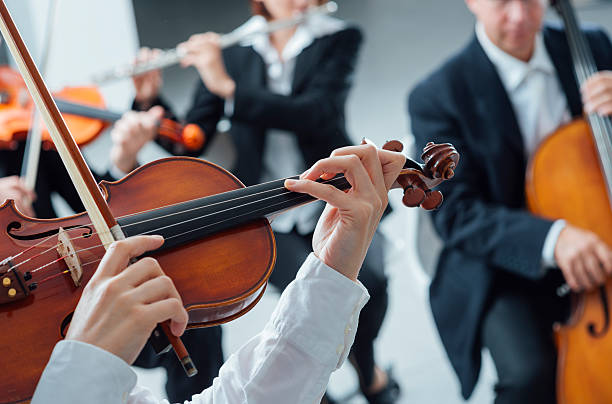 Classical orchestra string section performing Classical music symphony orchestra string section performing, female violinist playing on foreground, hands close up symphony orchestra photos stock pictures, royalty-free photos & images