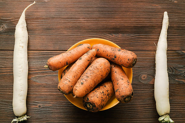Unpeeled carrots in a bowl and daikon radish