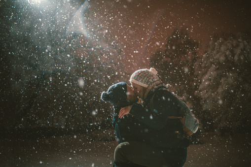 Loving couple is kissing and hugging to warm themselves on a cold snowy winter night