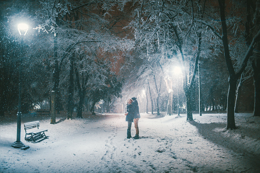 Loving couple is hugging to warm themselves on a cold snowy winter night