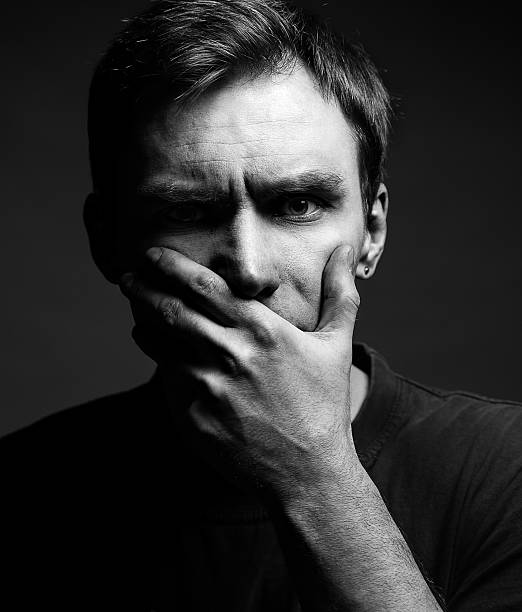istock Afraid male victim human with hand covering his mouth 588581180