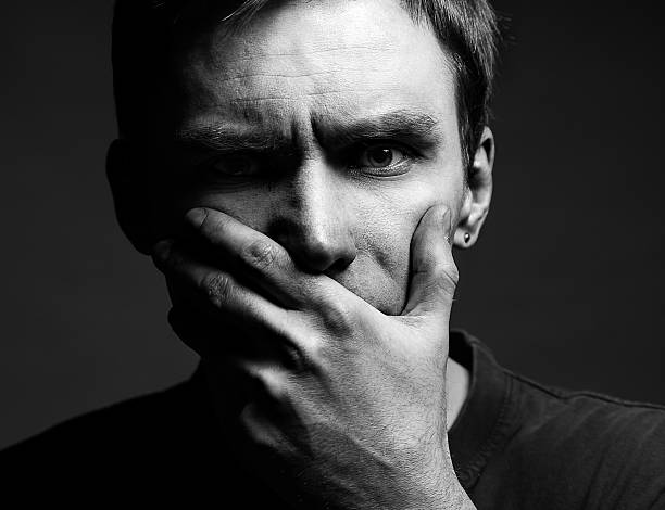 istock Afraid male victim human with hand covering his mouth 588581404
