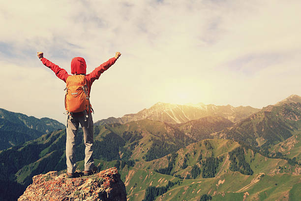 istock successful young woman backpacker open arms on mountain peak 588585526