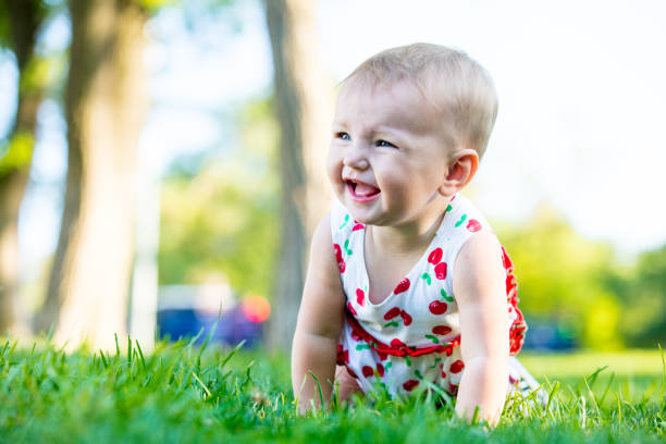 Cute little girl playing in the garden in a green grass backyard, making funny faces of curiosity.