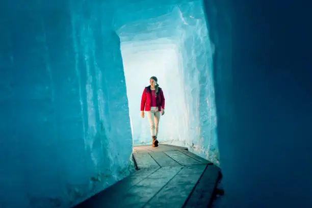 Young Woman Hiking Through Glacier Cave.