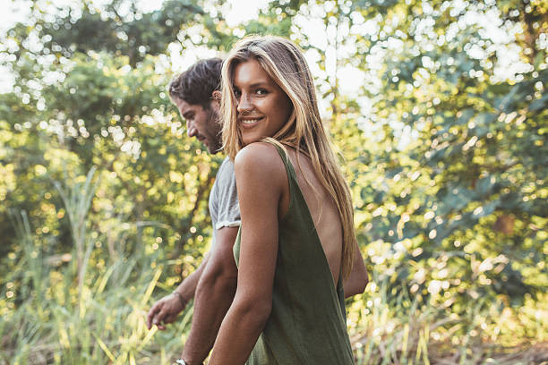 Attractive young couple walking together in countryside Portrait of attractive young woman walking with her boyfriend outdoors. Young couple together out in countryside. summer forest stock pictures, royalty-free photos & images