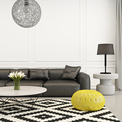 Square composition showing eclectic black and white living room with yellow cushion stool, with ornate elements around. Striped carpet over white floor, a lamp, flowers in a glass vase, with classic wall with ornate elements.
