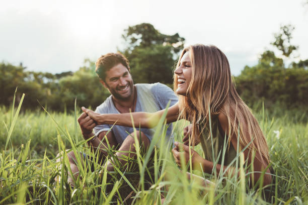 Loving young couple having fun outdoors Shot of loving young couple having fun outdoors in grass field. Man and woman enjoying a day in meadow. peace park stock pictures, royalty-free photos & images