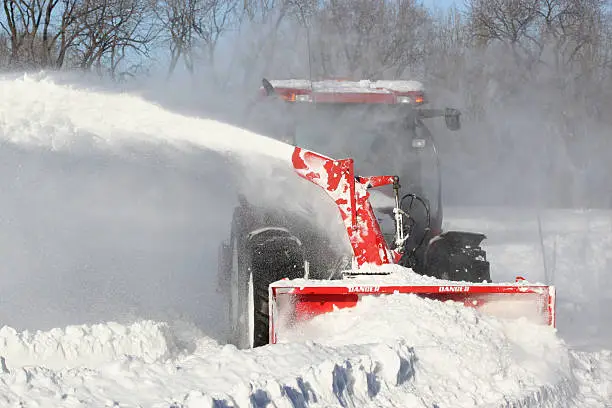 Red snow blower clears snow-covered streets in Montreal, Canada.