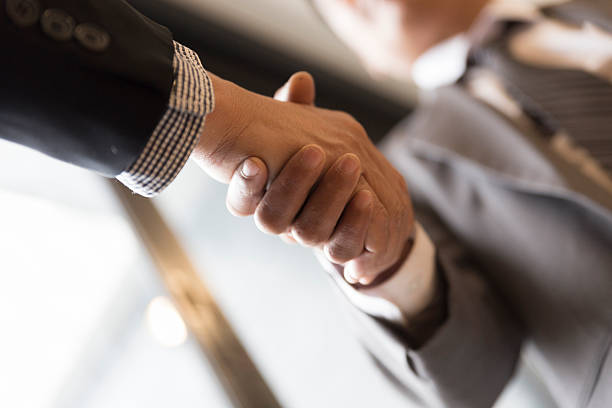 istock businessmen in suit shaking hands beside window - 588594018
