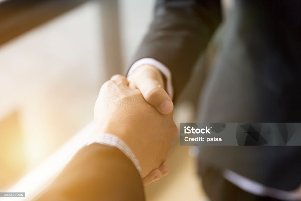 businessmen in suit shaking hands beside window - two businessman in suit shaking hands beside window - business teamwork, cooperation concept Agreement Stock Photo