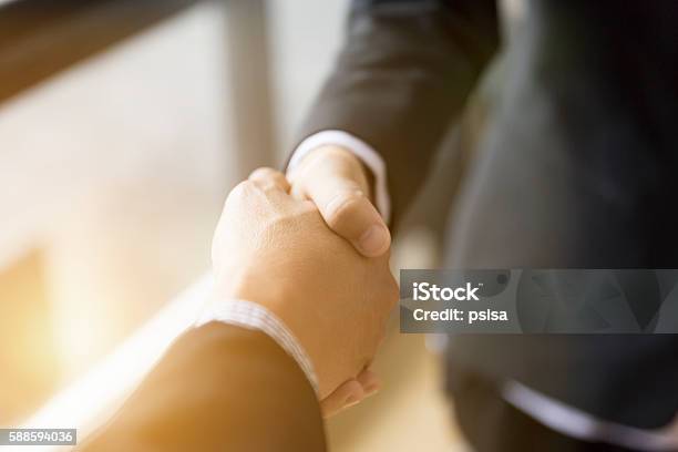 Businessmen In Suit Shaking Hands Beside Window Stock Photo - Download Image Now - Agreement, Business, Mergers and Acquisitions