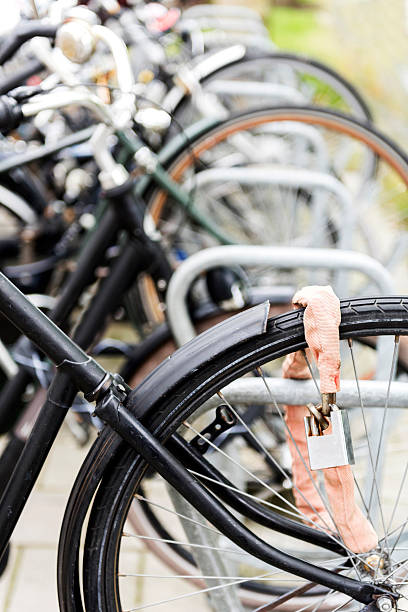A broken bike is locked to the railing at the river in the city center. The front wheel was stolen.