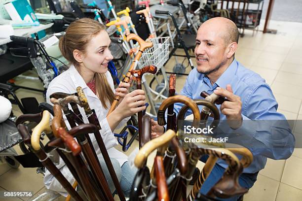 Physician Offering Cane To Customer Stock Photo - Download Image Now - Walking Cane, Selling, Store
