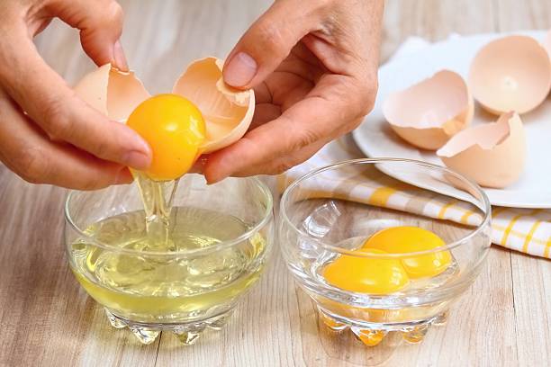 istock Woman hands breaking egg to separate  egg- white and  yolk 588597198