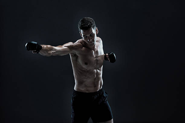 istock Shirtless muscular man punching 588597250
