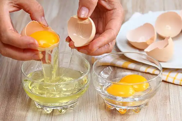 Photo of Woman hands breaking egg to separate  egg-white and  yolk