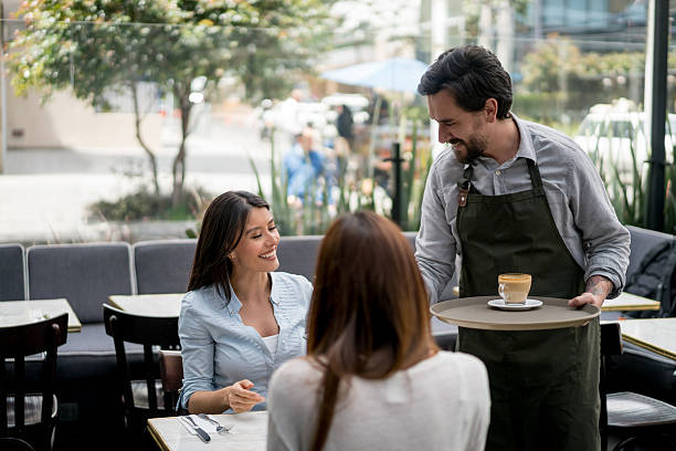 istock Waiter serving coffee to women at a cafe 588598052