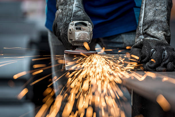 Industrial worker cutting metal with many sharp sparks stock photo