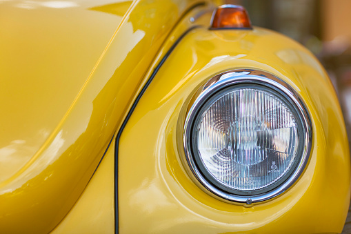 Sigtuna, Sweden - July 6, 2016: Front detail of a yellow classic Volkswagen Beetle standing on parking lot. The beetle was produced by Volkswagen between 1938 and 2003.