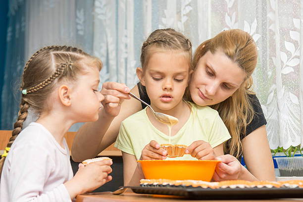 istock Mother and two children baking pour the mass into 588603520