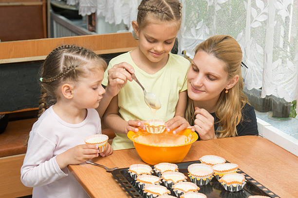 istock The elder daughter pours batter for cakes in tins 588603634