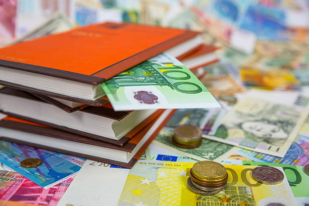Books and one hundred euro bill and coins on the bills background
