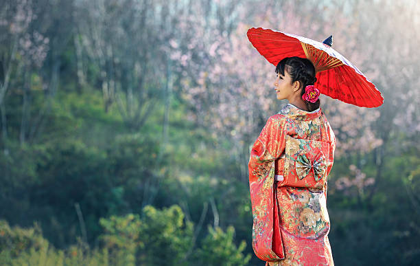 Asian woman wearing traditional japanese kimono, sakura background stock photo