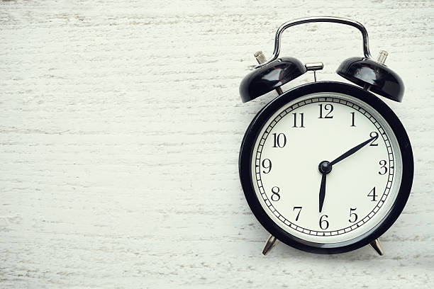 istock Retro alarm clock on wooden table 588614904