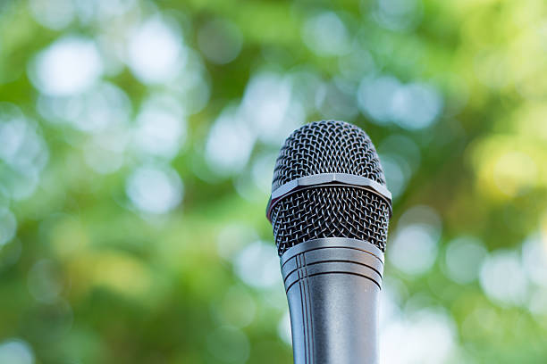 istock Black microphone in a park with defocused bokeh on background 588615974