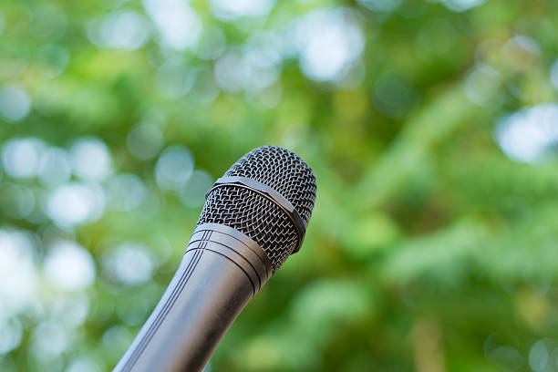 istock Black microphone in a park with defocused bokeh on background 588616230