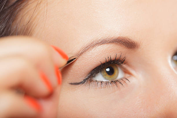 istock Girl tweezing eyebrows closeup 588619956