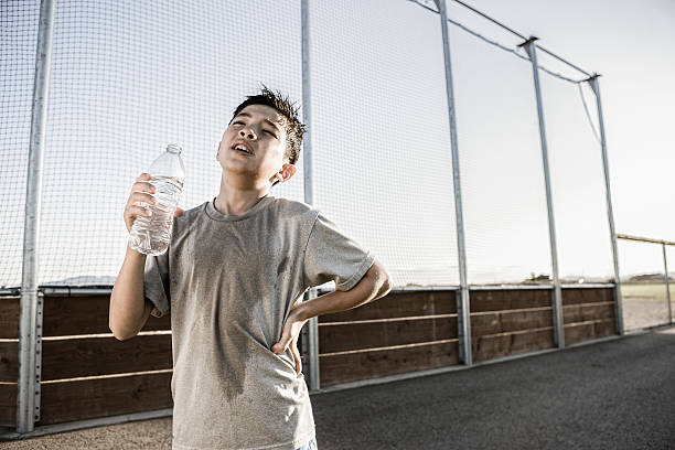 Boy shows exhaustion after practice. A young boy shows how tired he is after a hard practice. quench your thirst pictures stock pictures, royalty-free photos & images