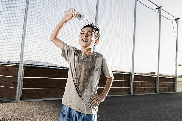 istock Boy cools off with water over his head. 588622240
