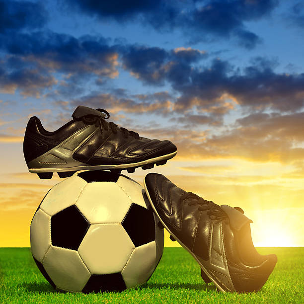 istock Soccer ball and shoes in grass 588622290