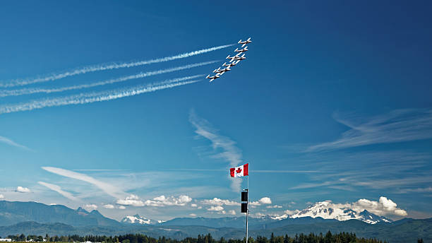 Snowbirds flying in formation over the Canadian Rocky Mountains Abbotsford, British Columbia, Canada - August 13, 2016: Canadian Forces Snowbirds aerial demonstration team in formation over the Canadian Rocky Mountains at the Abbotsford International Airshow. stunt airplane airshow air vehicle stock pictures, royalty-free photos & images