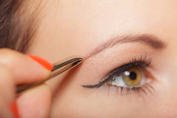 istock Girl tweezing eyebrows closeup 588624818
