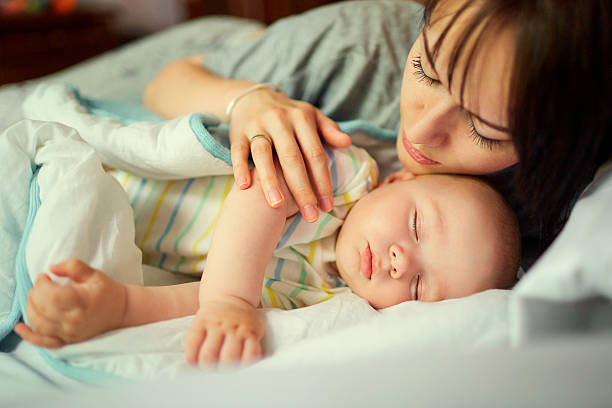 istock Baby sleeping in bed with mother. Care. 588625016