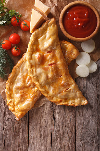 istock pizza calzone on a paper and ingredients. Vertical top view 588625114