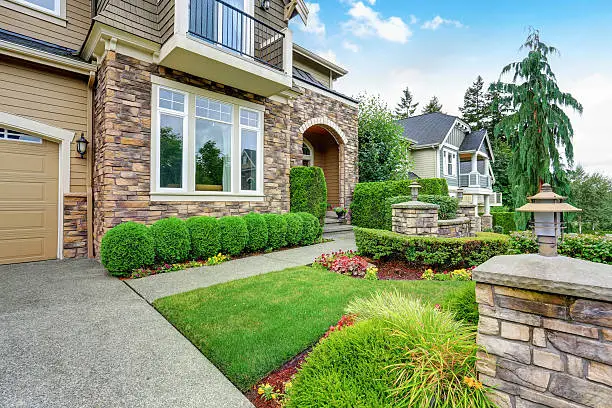 Beautiful curb appeal of American house with stone trim and perfectly trimmed shrubs. Northwest, USA