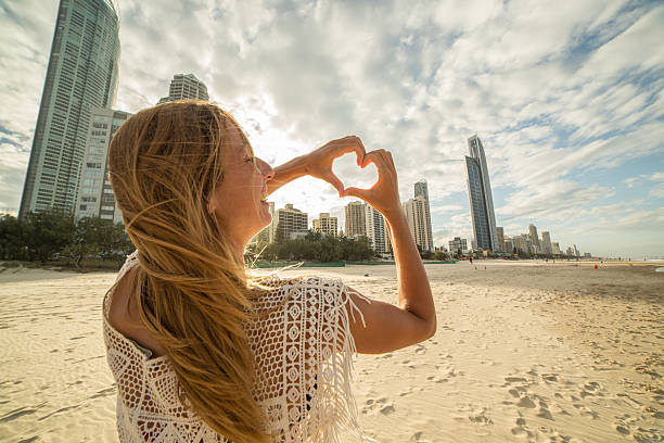 istock Young woman frames Surfers paradise beach into heart shape 588957490
